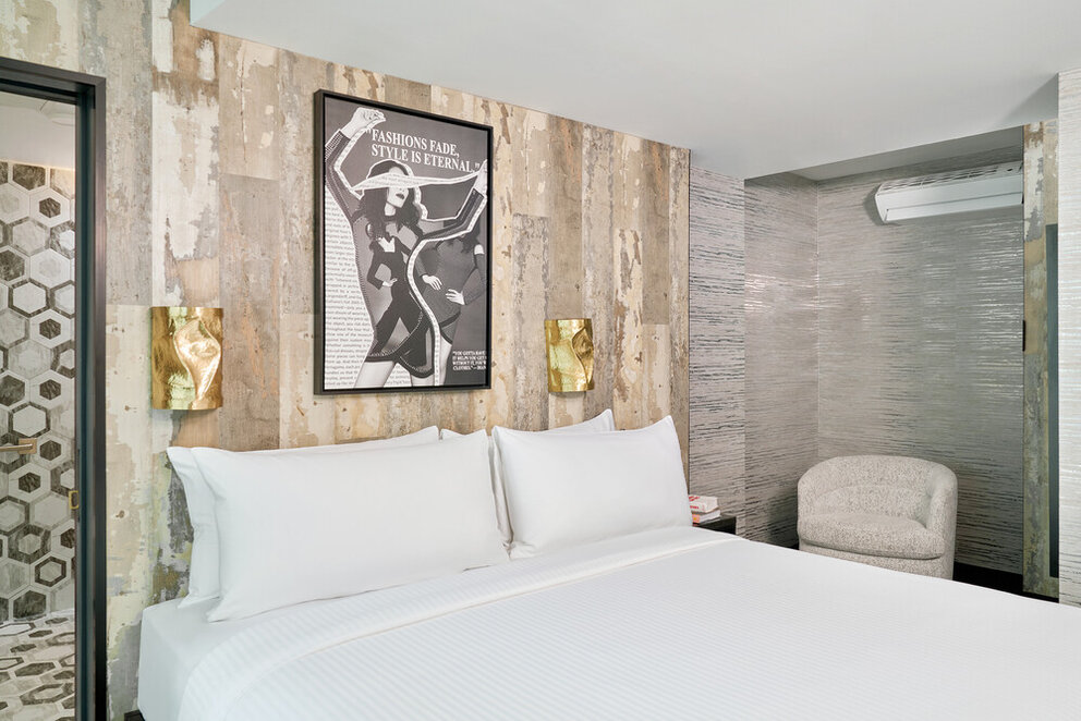 a bed with white sheets and a poster on the wall