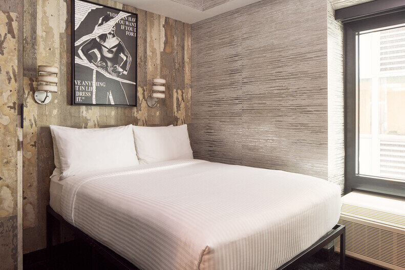 a bed with white sheets and a poster on the wall