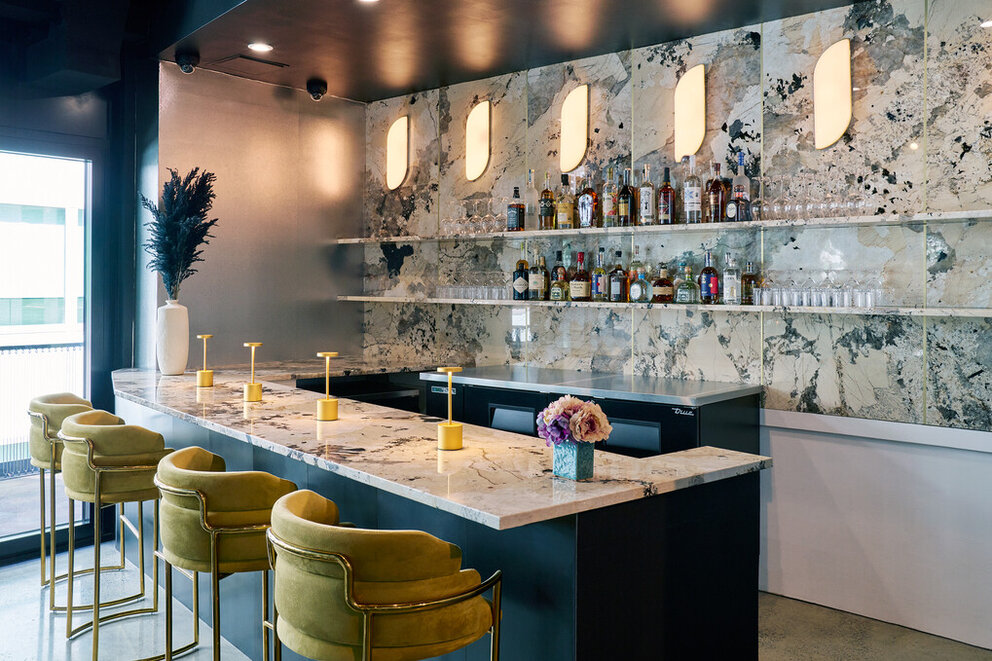 a bar with a marble counter and chairs