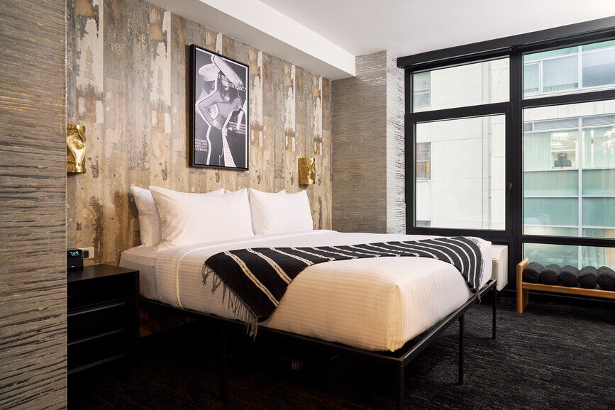 a bed with a striped blanket and a picture on the wall